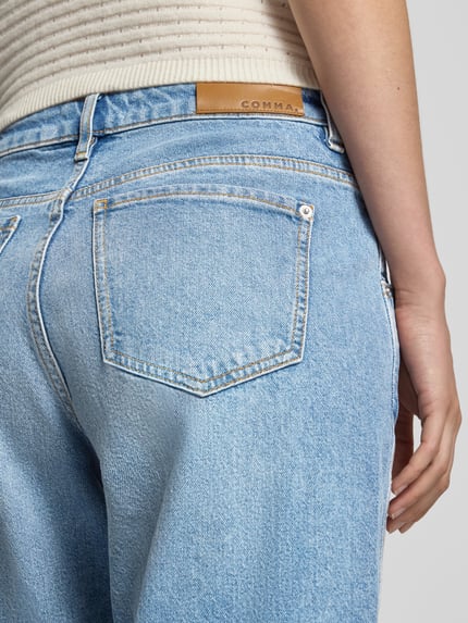 Frauenmodel trägt Wide Fit Jeans aus Baumwoll-Mix von COMMA in hellem Blau, sichtbare Gesäßtasche, Nahaufnahme Rückansicht, Damen Jeans von COMMA, elastischer Baumwoll-Mix, Eingriff- und Gesäßtaschen, Knopf- und Reißverschluss, Bundweite bei Größe 36: 38 cm, Innenbeinlänge bei Größe 36: 69 cm.