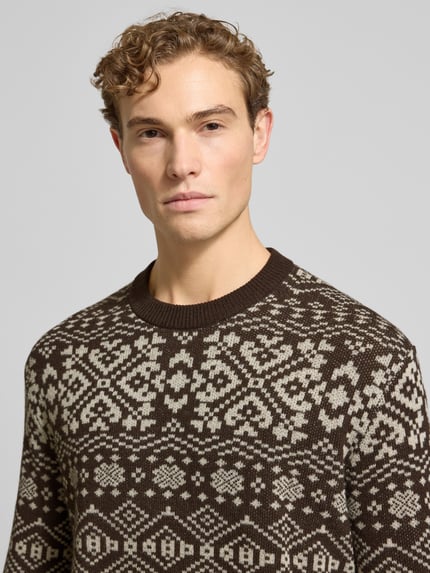 Männermodel trägt Regular Fit Strickpullover aus Woll-Mix Modell 'HOLGER' von SELECTED HOMME in Braun mit Jacquardmuster, Nahaufnahme Oberkörper.