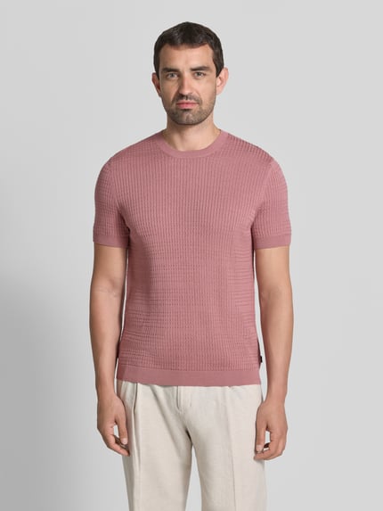 Männermodel trägt Strickshirt mit Strukturmuster Modell 'Elio' von JOOP! COLLECTION in Rosa, reine Baumwolle, Slim Fit, Rundhalsausschnitt, Ganzkörperansicht von vorne.