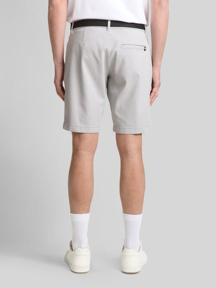 Męski model nosi Regular Fit Chinoshorts aus Baumwoll-Mix od Tom Tailor Denim, bi-color, pasek, kieszenie boczne i tylna, widok całej sylwetki z tyłu.