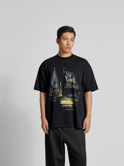 Männermodel trägt Relaxed Fit T-Shirt aus Baumwolle von VETEMENTS, schwarzes Herren T-Shirt mit Motiv-Print und Rundhalsausschnitt, Ganzkörperansicht von vorne.