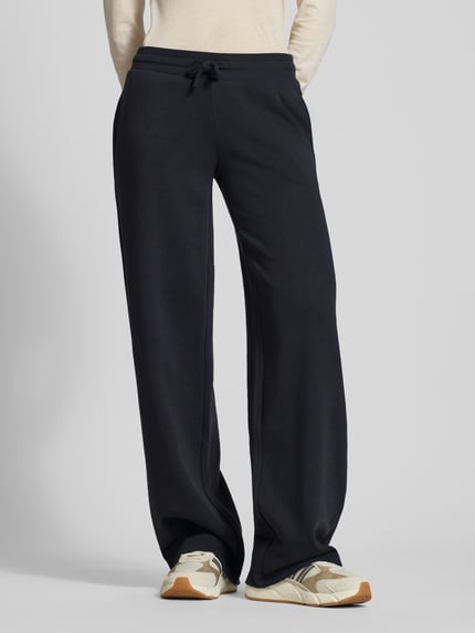 Vrouwenmodel draagt Wide Fit Sweatpants met viscose van Review, dames sweatpants in donkerblauw, elastische band met tunnelkoord, binnenbeenlengte maat S 89 cm, katoenmix met viscose, wide fit, comfortbroekdesign. Volledige vooraanzicht.