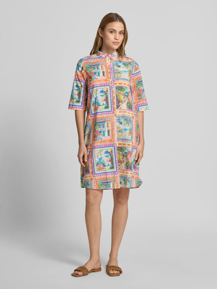 Modelka nosi knielanges Kleid aus reiner Viskose od Emily Van den Bergh, kolorowy wzór, luźny krój, stójka, listwa guzikowa, rękaw o dł. 3/4, długość do kolan, długość tyłu w rozmiarze 36: 103 cm, szerokość w rozmiarze 36: 49 cm, długość rękawów w rozmiarze 36: 40 cm. Ganzkörperansicht z przodu.