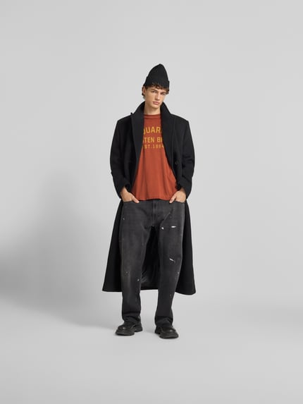 Männermodel trägt T-Shirt mit verstärktem Schultern von Dsquared2, lockere Passform, Logo-Print, Baumwolle, Ganzkörperansicht von vorne.
