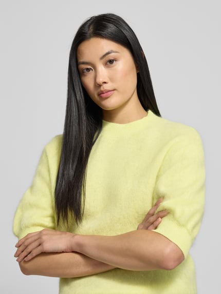Kobiece model prezentuje Strickpullover aus Wolle mit 1/2-Arm od Herzensangelegenheit, kolor jasnożółty, regular fit, półrękaw, okrągły dekolt, widok na górną część ciała z przodu.