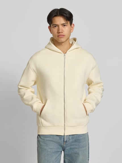 Männermodel trägt Sweatjacke mit Label-Print von REVIEW in Creme, Baumwoll-Mix, Gerader-Schnitt, Kapuze, Eingrifftaschen, Gerippte-Abschlüsse, Ganzkörperansicht von vorne.