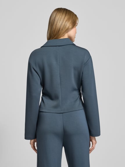 Frauenmodel trägt Cropped Blusenshirt mit Umlegekragen und Knopfleiste von Scotch & Soda im Material-Mix mit Micromodal-Anteil, Rückenlänge bei Größe S 48 cm, Ärmellänge 56 cm, blauer Farbton, glatte Textur, Ganzkörperansicht Rückansicht.