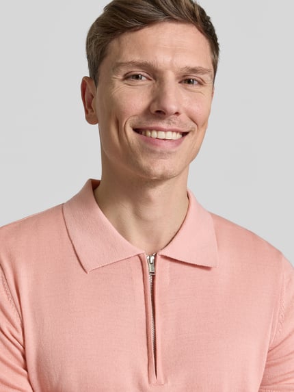 Männermodel trägt Regular Fit Poloshirt aus reiner Wolle Modell 'TRAY' von SELECTED HOMME in Rosa, Strick, Nahaufnahme Oberkörper.