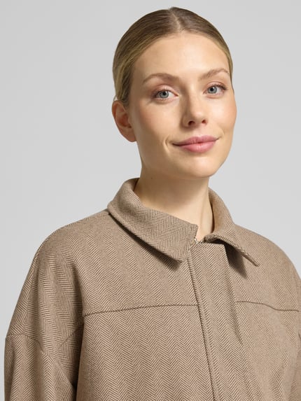 Frauenmodel trägt Regular Fit Jacke mit verdecktem Reißverschluss Modell 'Cl44aire' von ZABAIONE, beige Fischgrätmuster, Nahaufnahme Oberkörper. Rückenlänge 54 cm, Schulterbreite 62 cm, Brustweite 59 cm, Ärmellänge 48 cm.