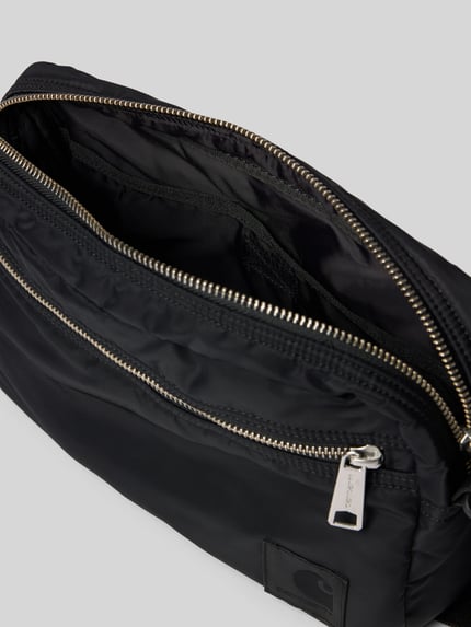 Produktfoto, Tasche mit Logo-Print von Carhartt Work In Progress in Schwarz, glatte wasserabweisende Oberfläche, silberner Reißverschluss, zeigt Hauptfach und Logo-Patch, Hauptfach mit Reißverschluss, verstellbarer Schulterriemen, Maße 28 x 21 x 7 cm, Schulterriemen 126 cm.