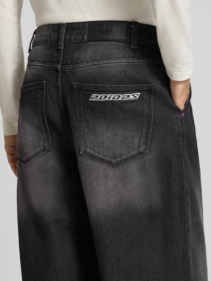 Männermodel trägt Regular Fit Jeans mit Bundfaltenoptik von Adidas Originals, Denim in Faded-Optik, 5-Pocket-Design, Nahaufnahme Rückansicht.