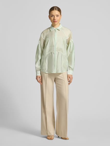 Kobiece modelka nosi Regular Fit bluzka z kołnierzykiem koszulowym, listwa guzikowa kryta, model 'MOLLY' od Copenhagen Muse, długość tyłu 67 cm, długość rękawów 76 cm, widok całej sylwetki z przodu.