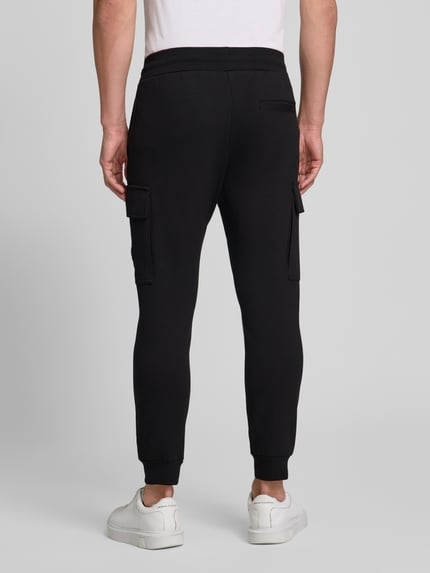 Männermodel trägt Regular Fit Sweatpants mit Cargotaschen von Antony Morato in Schwarz aus Baumwoll-Mix, Ganzkörperansicht Rückansicht.