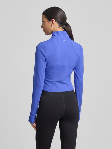 Frauenmodel trägt Slim Fit Jacke mit Stehkragen Modell 'Storm' von Fabletics, leuchtendes Blau, glatte Textur, cropped, Daumenschlaufen, Ganzkörperansicht Rückansicht, Kontext: Damen Jacke, Rückenlänge 44 cm, Schulterbreite 36 cm, Brustweite 42 cm, Ärmellänge 74 cm bei Größe S.