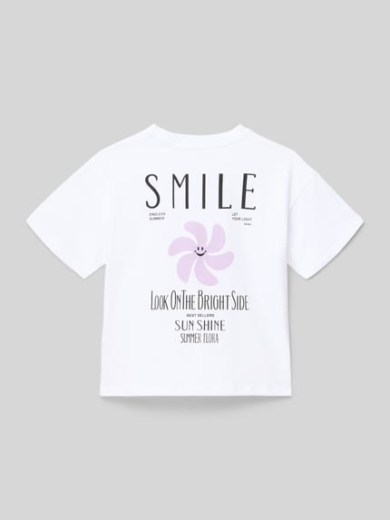 Mädchen trägt Regular Fit T-Shirt aus reiner Baumwolle Modell 'SUN-VERAS' von Only in Weiß mit Motiv-Print, Ganzkörperansicht Rückansicht.