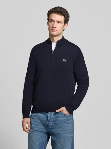 Männermodel trägt Pullover mit Troyerkragen BASIC KNIT TROYER von LACOSTE in Dunkelblau, unifarben, Strukturmuster, Logo-Patch, Feinstrick, Ganzkörperansicht von vorne.