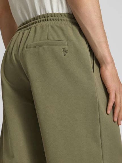 Männermodel trägt Shorts mit elastischem Bund und Ziernähten von REVIEW, Material-Mix mit Stretch-Anteil, Nahaufnahme Rückansicht.