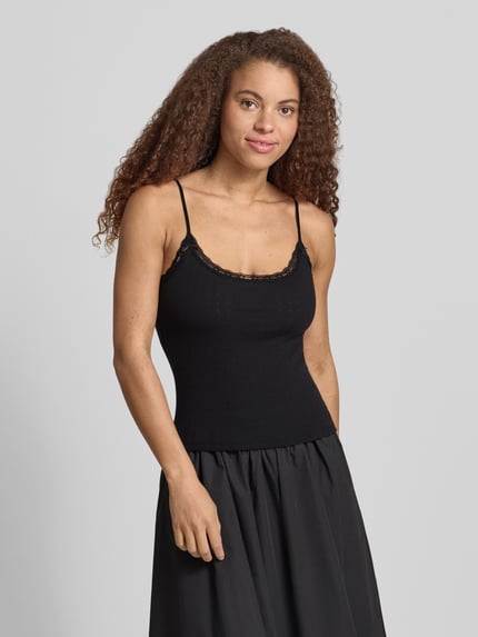 Frauenmodel trägt Slim Fit Top mit Spitzenbesatz von REVIEW, Reine Baumwolle, Spaghettiträger, Zierschleifen, schwarze Farbe, Ganzkörperansicht von vorne.
