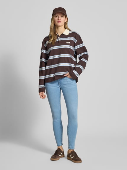 Frauenmodel trägt Slim Fit Jeans mit Logo-Patch von Calvin Klein Jeans im hellblauen Baumwoll-Mix, 5-Pocket-Design, Knopf- und Reißverschluss, Ganzkörperansicht von vorne.