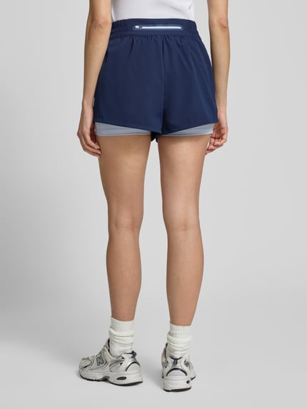 Vrouwenmodel draagt Regular Fit Sport-Shorts met Logo-Applikation van Lacoste Sport, uni blauw, piqué/stretch, met zakken, elastische taille, geheellichaamsfoto achteraanzicht.