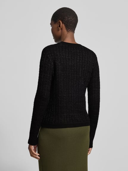 Frauenmodel trägt Cardigan mit goldfarbenen Zierknöpfen von Anine Bing in schwarzer Strickoptik mit Struktur, Ganzkörperansicht Rückansicht.