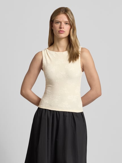 Vrouwenmodel draagt Slim Fit Top met floralem allover-stitching model 'Jacquard' van Gina Tricot, elastische materiaalmix, slim fit, ruglengte bij maat S 47 cm, voorkant bovenlichaam close-up.