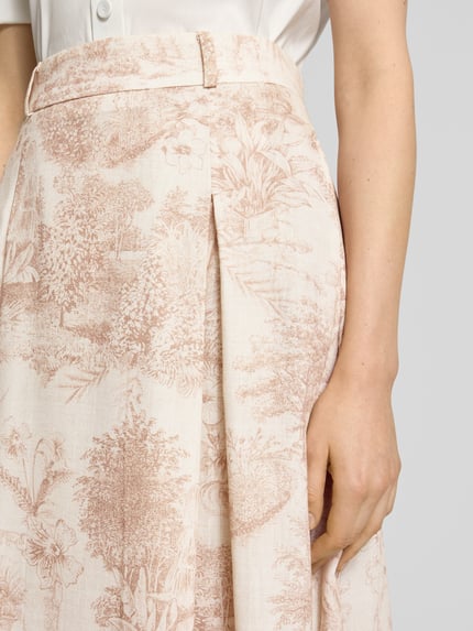 Frauenmodel trägt Midirock im Allover-Look Modell 'PALMIRA' von SEDUCTIVE, A-Linie, Gelegte Falten, Nahaufnahme Oberkörper. Kontext: Damen Midirock, Bundweite bei Größe 36: 39 cm, Gesamtlänge bei Größe 36: 88 cm.