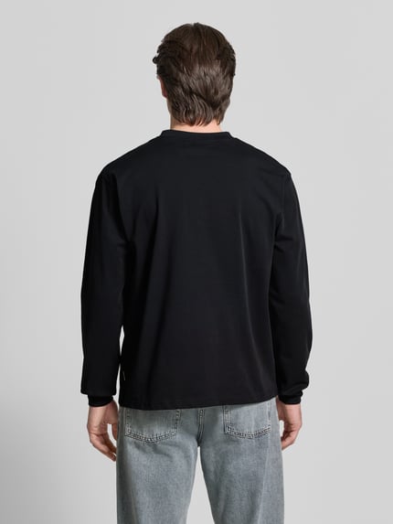 Männermodel trägt Longsleeve mit Label-Stitching Modell 'Baine' von WOODBIRD in Schwarz, reine Bio-Baumwolle, Rückansicht Ganzkörperansicht.