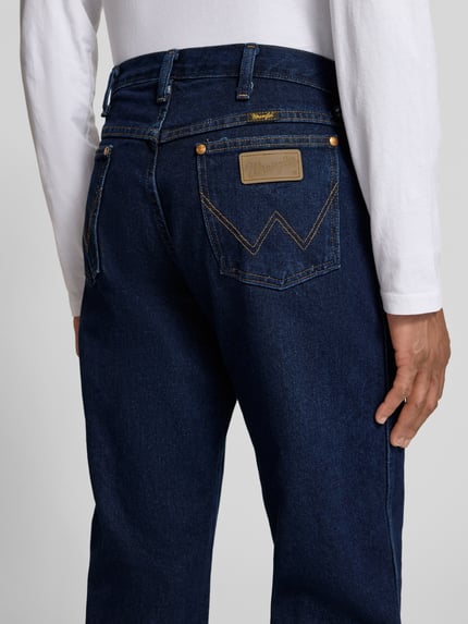 Mannenmodel draagt Cowboy Cut Jeans im 5-Pocket-Design van Wrangler, rechte pasvorm, katoenen denim, donkerblauw, detailopname achterkant.