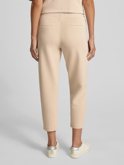 Kobieta prezentuje Cropped Sweatpants mit elastischem Bund und Eingrifftaschen od Christian Berg Woman, mieszanka materiałów z domieszką modalu, krótki krój, elastyczny pas, wpuszczane kieszenie, jasny beż, gładka faktura, Ganzkörperansicht Rückansicht.