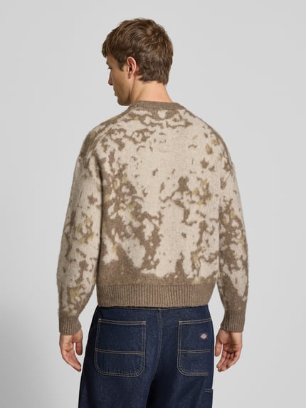 Männermodel trägt Pullover mit gerippten Abschlüssen von ONLY im mehrfarbigen Used Look mit abstraktem Allover-Muster, Strickoptik, Ganzkörperansicht Rückansicht.