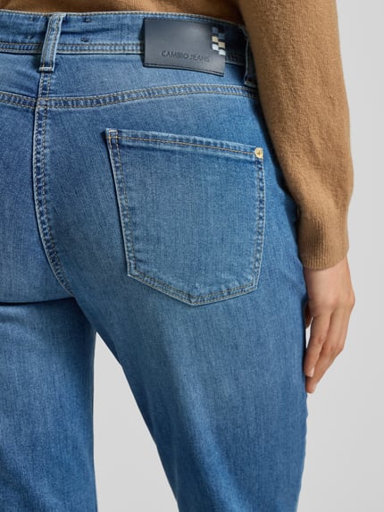 Vrouwenmodel draagt Jeans in verkorte pasvorm van Cambio, katoenmix met stretch, 5-pocketmodel, blauwe denim, detailopname achteraan.