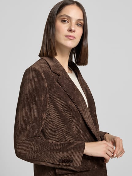 Frauenmodel trägt Regular Fit Blazer aus Cord Modell 'GLENDALE' von DRYKORN in Braun mit Reverskragen und Pattentaschen, Nahaufnahme Oberkörper.
