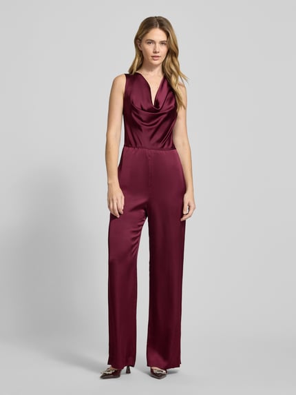Modelka kobieca nosi bordowy, taliowany damski jumpsuit z satyny z kokardą i wodospadowym dekoltem, Kimari-1 od HUGO, pełen widok z przodu.