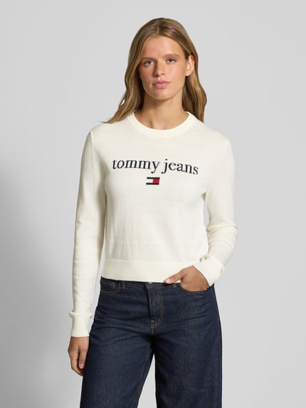 Modelka kobieca ma na sobie Regular Fit Pullover aus Baumwoll-Mix od Tommy Jeans, kolor ecru, gładka faktura, widok całej sylwetki z przodu. Sweter damski od Tommy Jeans.
