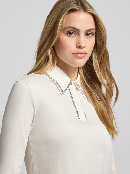 Kobiece model prezentuje Blusenshirt mit Umlegekragen und Ziersteinbesatz od Marc Cain z bawełny, regular fit, 3/4 rękaw, jasny kolor. Nahaufnahme górnej części ciała.