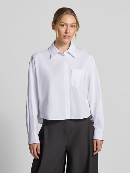 Frauenmodel trägt Relaxed Fit Hemdbluse aus Viskose-Mix Modell 'Anna' von MANGO, weiß, Brusttasche, Ganzkörperansicht von vorne.