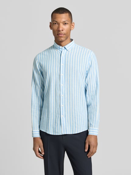 Männermodel draagt Relaxed Fit vrijetijdsoverhemd met button-downkraag van Lindbergh, mix van linnen en katoen, knoopsluiting, sportmanchet, ruglengte maat M 64 cm, schouderbreedte 41 cm, mouwlengte 64 cm, lichtblauw met witte strepen, recht model, textuur met zichtbare weefstructuur. Ganzkörperansicht von vorne.