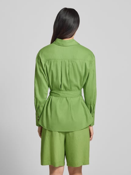 Frauenmodel trägt Bluse aus Leinen-Mix mit Brusttaschen von Marc Cain in leuchtendem Grün, taillierte Passform, Stoffband, Umlegekragen, Ganzkörperansicht Rückansicht. Rückenlänge bei Größe 36: 69 cm, Ärmellänge bei Größe 36: 55 cm, elastischer Leinen-Mix mit Viskose-Anteil.