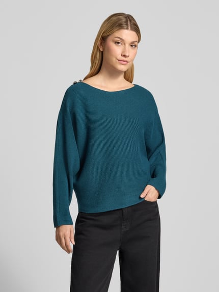 Kobiece model prezentuje Relaxed Fit Strickpullover aus Viskose-Mix mit Zierknöpfen od zero, mieszanka wiskozy, krój relaxed fit, marszczenia, ozdobne guziki, dekolt w łódkę, długość tyłu w rozmiarze S: 51 cm, długość rękawów w rozmiarze S: 50 cm, cała sylwetka od przodu.
