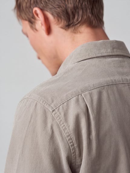 Männermodel trägt Regular Fit Businesshemd mit Cordstruktur von Seidensticker in Beige, feine Cordstruktur, Ganzkörperansicht Rückansicht.