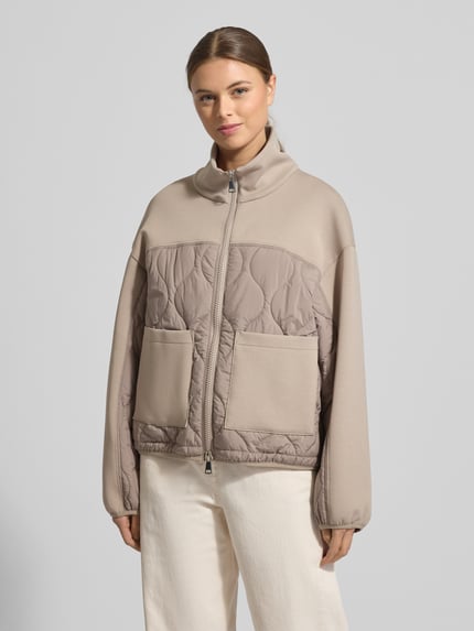 Vrouwenmodel draagt Jacke mit Steppnähten und Zweiwege-Reißverschluss van White Label, katoenmix met stretch, regular fit, opstaande kraag, doorgestikte naden, tweewegritssluiting, ruglengte 58 cm, schouderbreedte 49 cm, borstwijdte 50 cm, mouwlengte 67 cm, lichtbeige tinten, zachte textuur, grote zakken, geheel van voren te zien, ganzkörperansicht van voren.