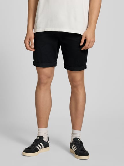 Männermodel trägt Shorts mit Gürtel Modell 'MIKE' von Redefined Rebel, schwarze Farbe, Eingrifftaschen, Regular-Fit, Nahaufnahme Oberschenkel, Kontext: Bundweite bei Größe M 43 cm, Innenbeinlänge 21 cm.
