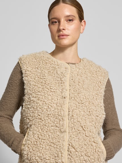 Frauenmodel trägt Weste aus Teddyfell Modell 'Vada' von LOLLYS LAUNDRY in Beige, strukturierte Oberfläche, Rundhalsausschnitt, Nahaufnahme Oberkörper, Damen Weste Regular Fit, Knopfleiste, Kontext: Rückenlänge 60 cm, Schulterbreite 46 cm, Brustweite 49 cm bei Größe S.