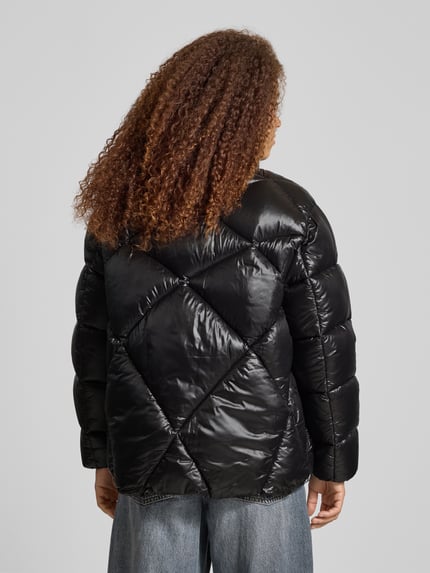 Frauenmodel trägt Oversized Steppjacke Modell 'FRESIA-1' von Hugo Blue, Optik: unifarben, wasserabweisend, Ganzkörperansicht Rückansicht.