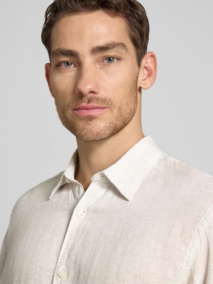 Männermodel trägt Regular Fit Leinenhemd aus reinen Leinen Modell 'Lawrence' von Jack & Jones Premium, Kentkragen, beige, Nahaufnahme Oberkörper.
