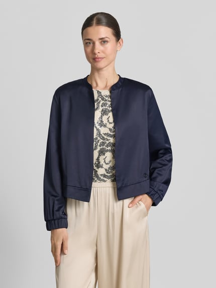 Frauenmodel trägt Slim Fit Blazer aus Viskose-Mix von s.Oliver BLACK LABEL in Optik: Unifarben, College-Kragen, Langarm, Label-Detail, ganzkörperansicht von vorne.