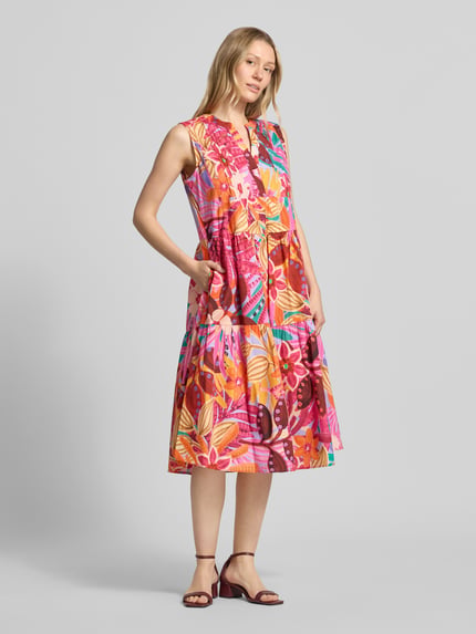 Frauenmodel trägt farbenfrohes Midikleid im Stufen-Look von Milano Italy aus elastischem Baumwoll-Mix, Taillierte Passform, Serafino-Ausschnitt, Rückenlänge 110 cm, Brustweite 47 cm bei Größe 36, Ganzkörperansicht von vorne.