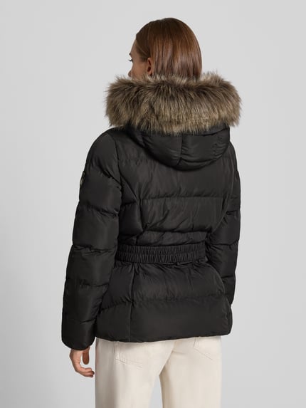 Frauenmodel trägt Mantel in Stepp-Optik Modell 'FUJI' von Superdry mit Kunstfellbesatz und Gürtel, schwarze Farbe, Ganzkörperansicht Rückansicht.
