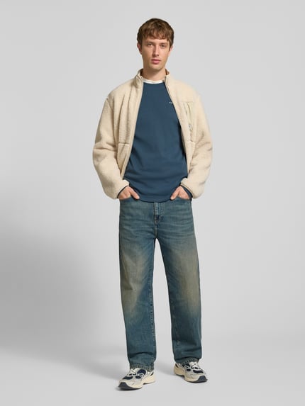 Männermodel trägt Langarmshirt mit kleinem Logo-Schriftzug von G-Star RAW in Dunkelblau, Regular Fit, Rundhals, Strukturmuster, Ganzkörperansicht von vorne.